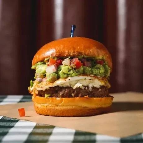 Gourmet burger with beef patty, fried egg, guacamole, and brioche bun.