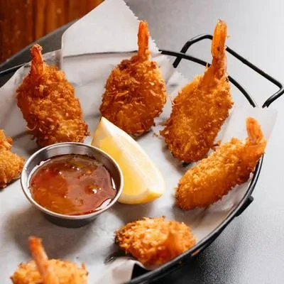 Golden-brown fried coconut shrimp served with sweet chili sauce and lemon.