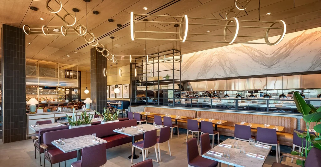 Upscale restaurant interior: dining area, bar, and open kitchen pass.