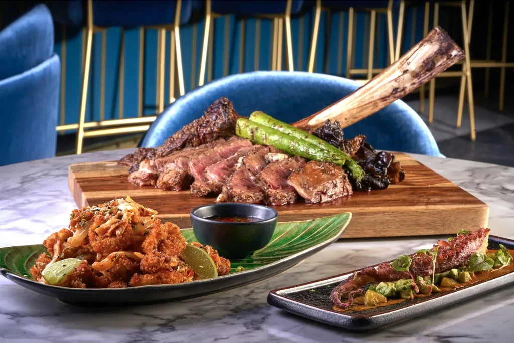 Artfully arranged gourmet sliced steak, fried items, and grilled octopus.