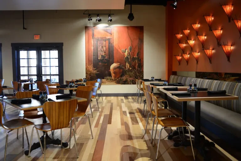 Empty modern restaurant with wood floor, colorful walls, and desert artwork.