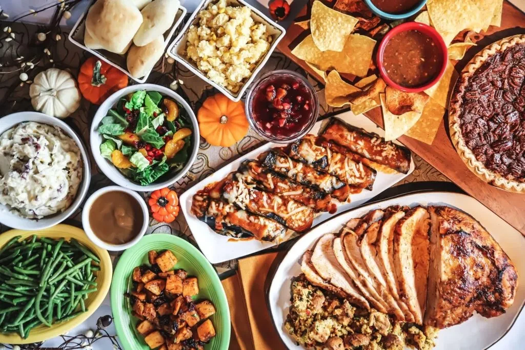 Overhead view of a Thanksgiving feast with turkey, pie, and diverse dishes.