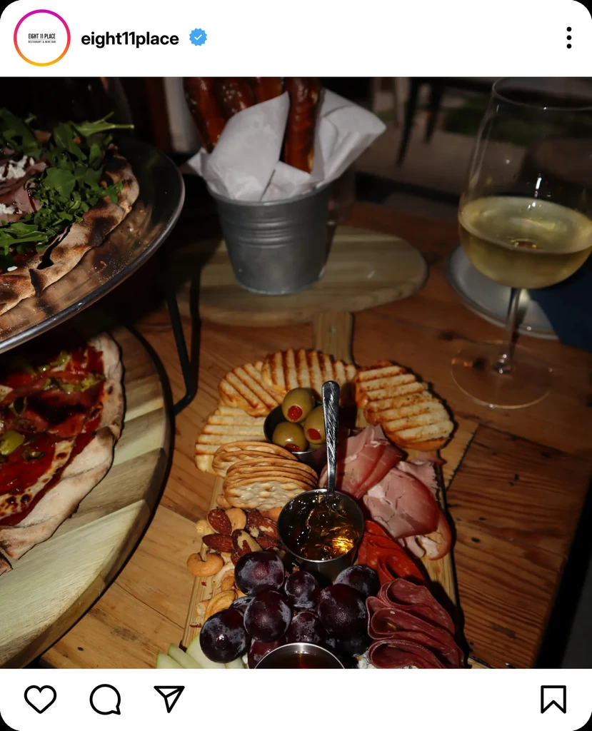 Rustic wooden table with pizzas, charcuterie board, pretzels, and wine.