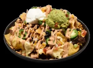 Close-up of nachos with cheese, meat, jalapeños, sour cream, and guacamole.