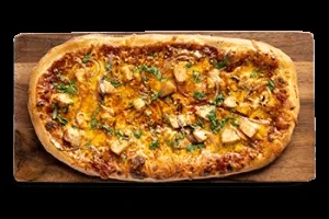 Overhead chicken flatbread pizza with cheese and herbs on wood.