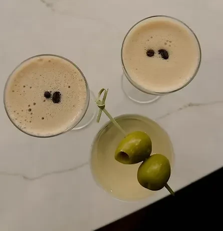Three martini glasses, two with coffee beans, one with olives.