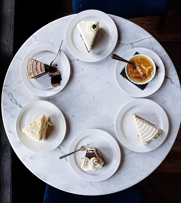 Overhead shot of six different desserts on a round marble table.