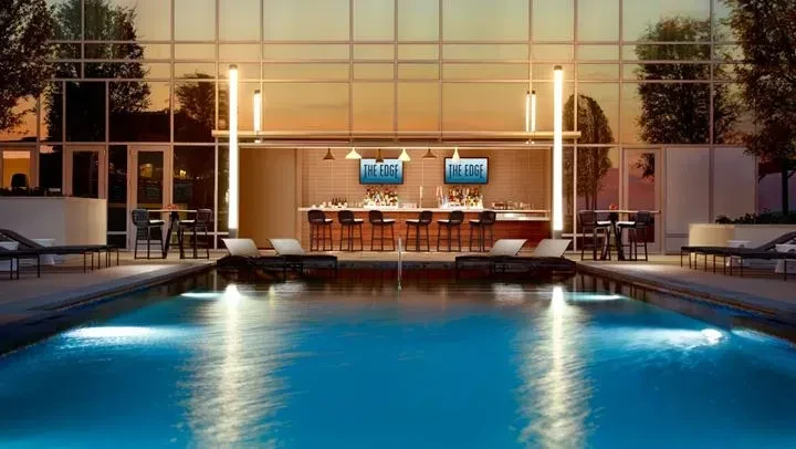 Luxurious outdoor bar 'THE EDGE' by an illuminated pool at dusk.