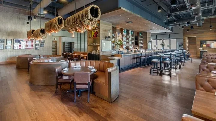 Upscale restaurant interior with bar, leather booths, and rustic industrial decor.