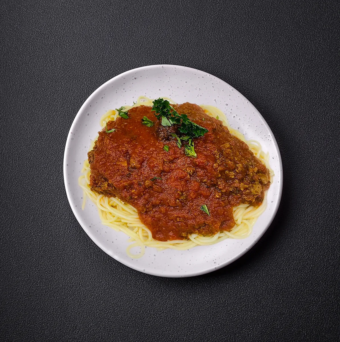 Spaghetti topped with meat sauce and fresh chopped parsley