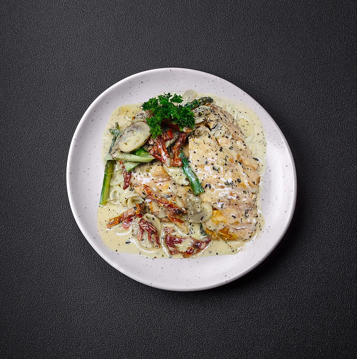 Chicken breast over linguine with cream sauce and asparagus