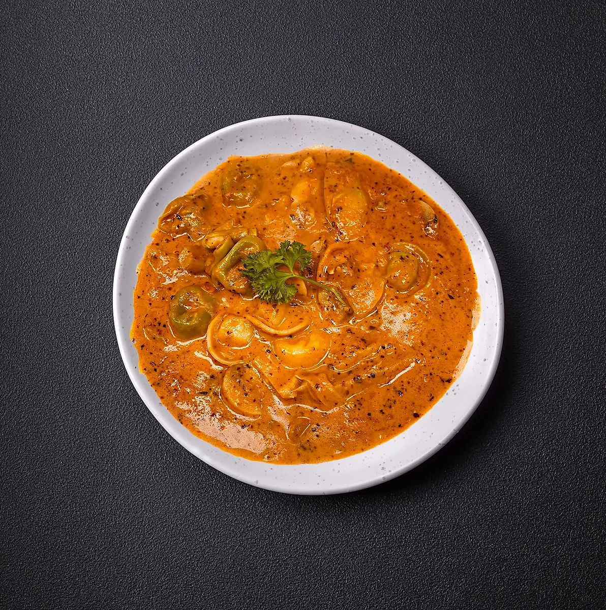 Tortellini in creamy tomato sauce with parsley on white plate