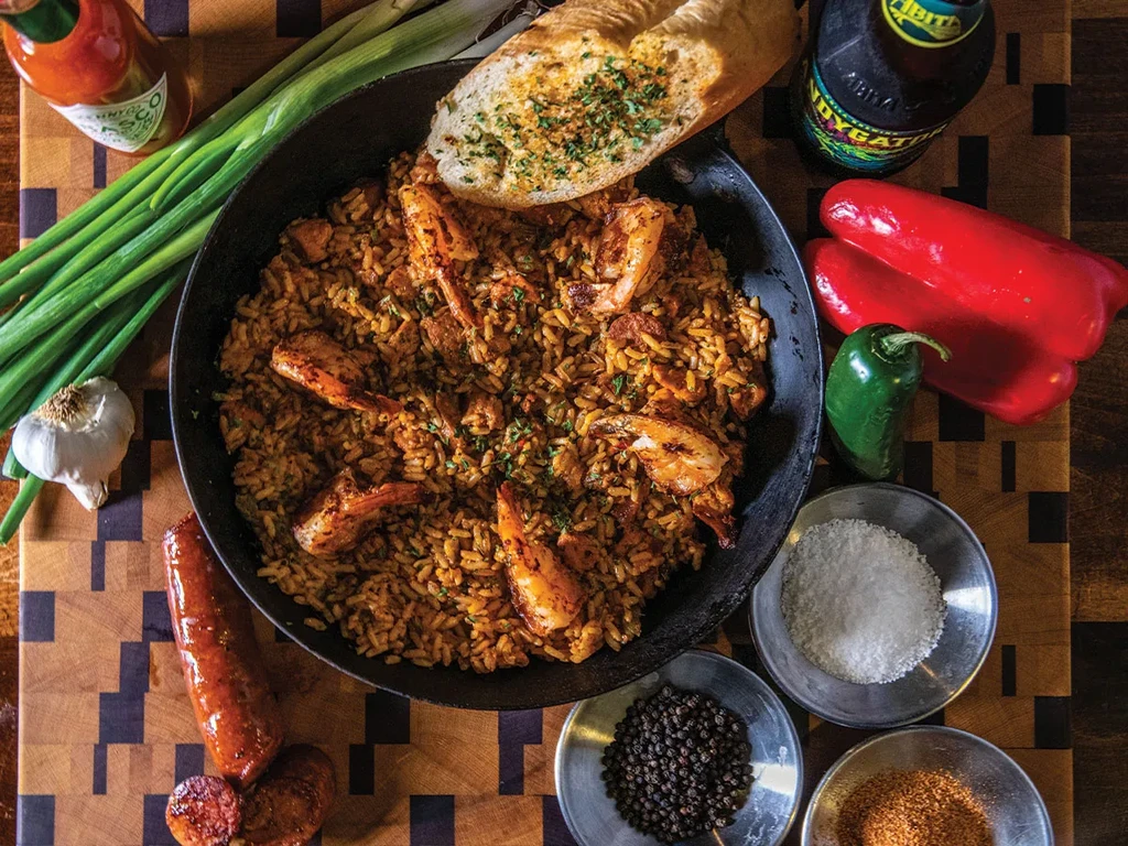 Overhead shot of jambalaya or paella with shrimp, garlic bread, and ingredients.