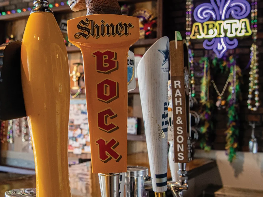 Beer tap handles including Shiner Bock and Rahr & Sons at a bar.