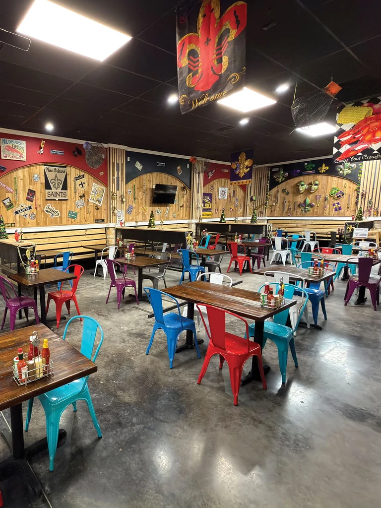 Vibrant, empty New Orleans-themed restaurant dining area with colorful chairs.