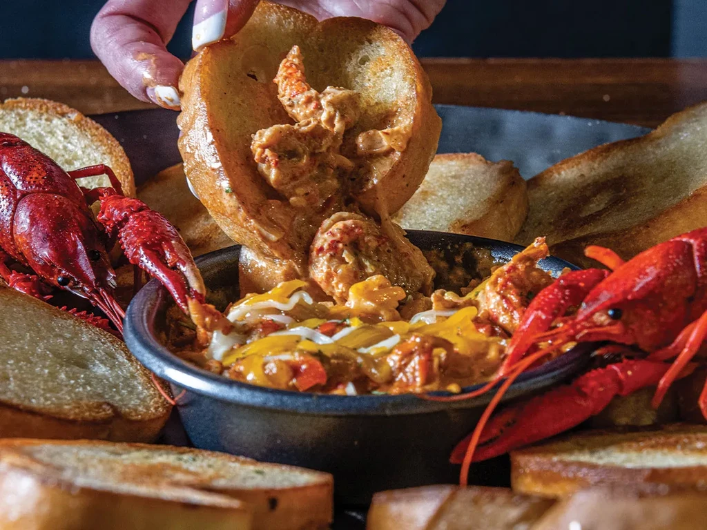 Creamy cheesy crawfish dip with toasted bread and whole cooked crawfish.