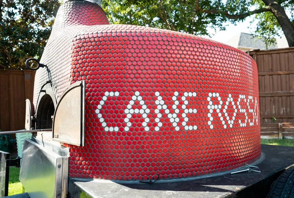Outdoor red mosaic mobile pizza oven with "CANE ROSSO" in white tiles.