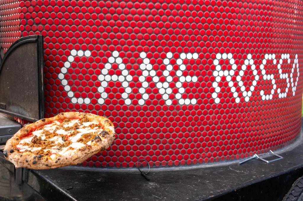Floating pizza with melted cheese, sausage, and CAVE ROSSI mosaic.