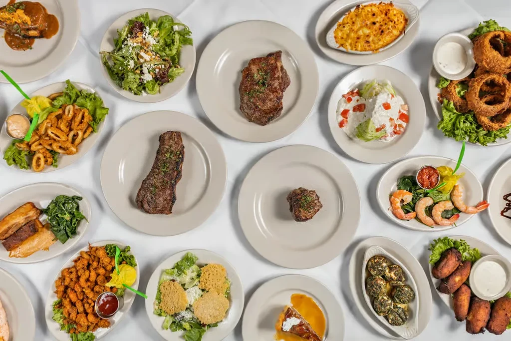 Overhead view: diverse restaurant meal spread with steak, salads, dessert.