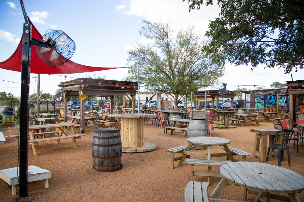 Spacious rustic outdoor patio with picnic tables, shade, and graffiti mural.