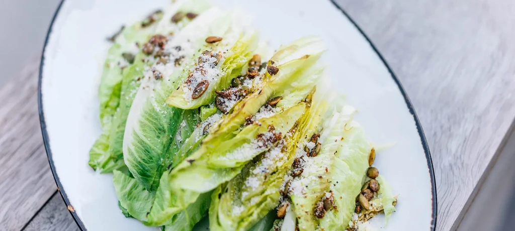 Close-up of grilled romaine salad with Parmesan and pumpkin seeds.
