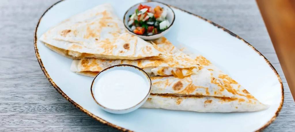 Toasted quesadilla triangles with melted cheese, salsa, and creamy dip.