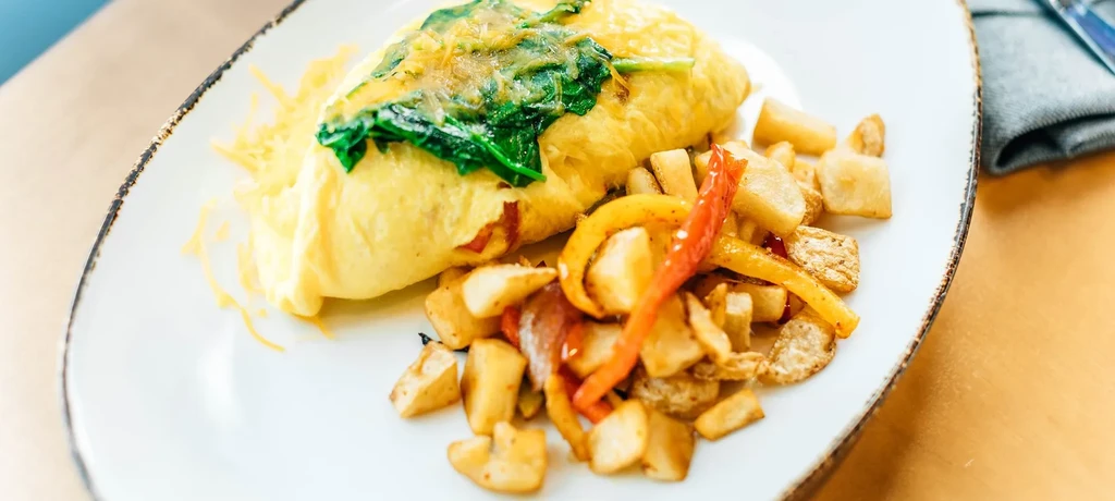 Spinach and cheese omelet with roasted potatoes and bell peppers.
