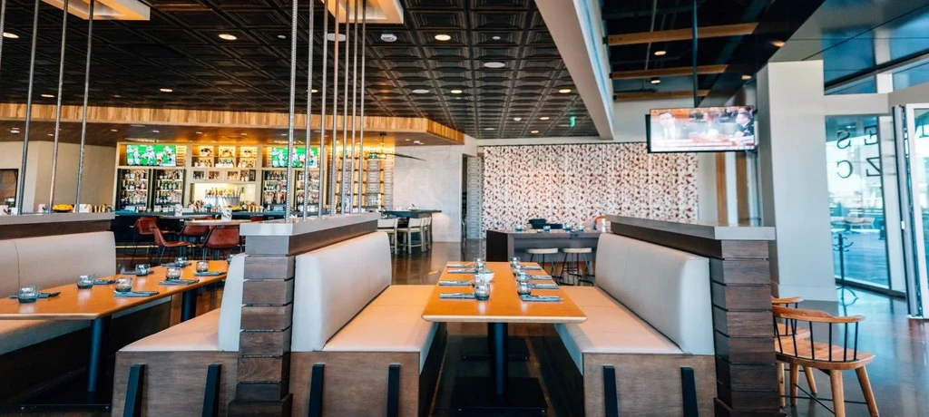 Empty modern restaurant with booth seating and a prominent bar.