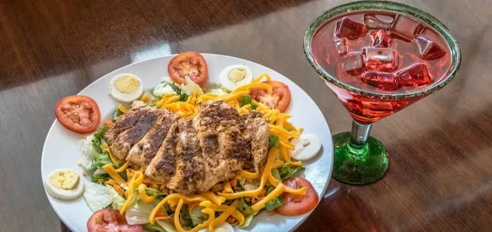 Chicken salad with egg, tomato, cheese, and a red iced drink.