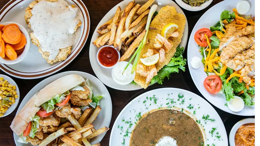 Overhead view of diverse Southern meals on a dark wooden table.