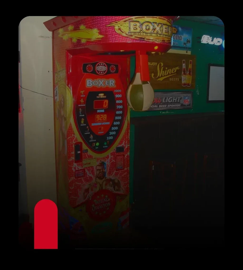 Arcade 'BOXER' punching machine surrounded by bar signs.