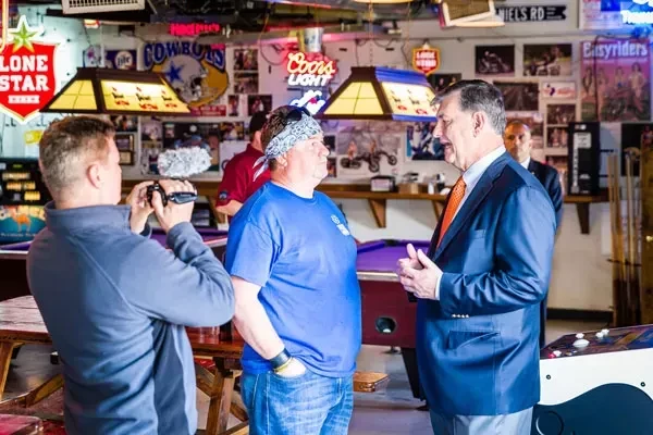 Man filming two men interviewing in a lively American pub.