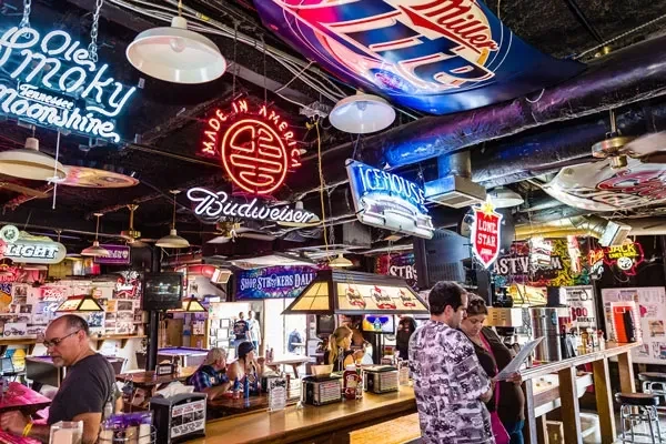 Busy bar interior with a ceiling covered in colorful neon signs.