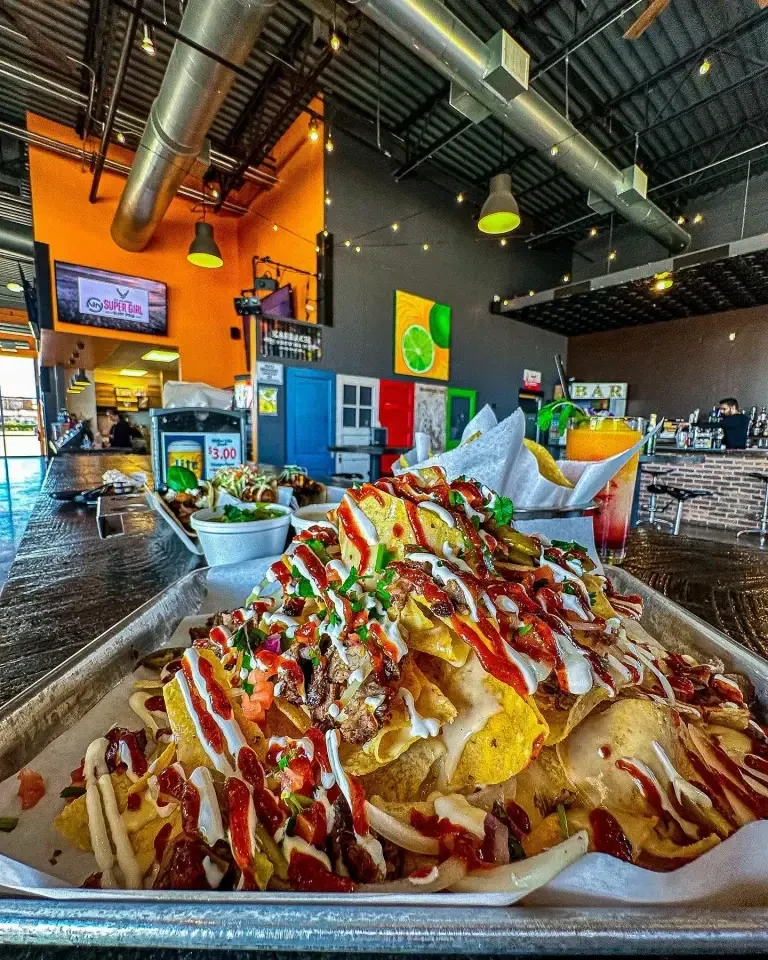 Overflowing tray of loaded nachos in a modern restaurant setting.