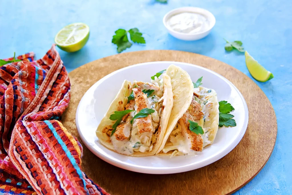 Two fish/chicken tacos with slaw, creamy sauce, lime, and parsley.