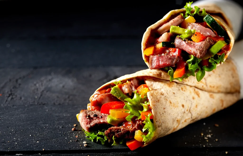 Two open wraps stuffed with medium-rare steak and colorful fresh vegetables.
