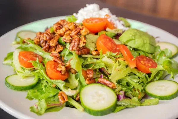 Fresh salad with greens, tomatoes, cucumber, avocado, feta, and candied nuts.
