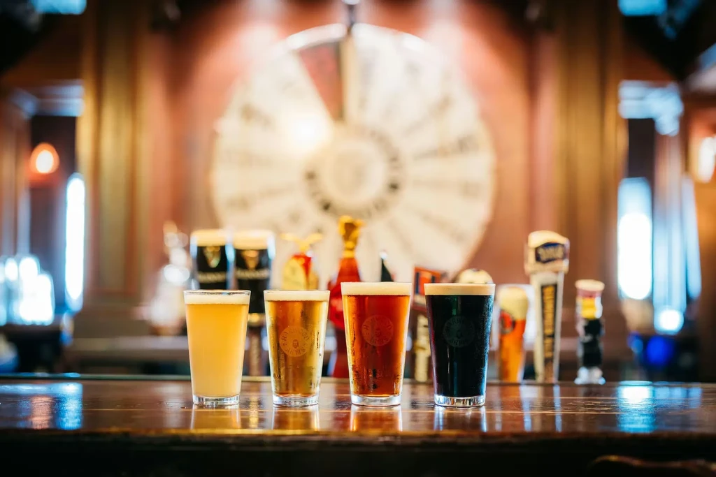 Four beers, from pale to dark, lined on a wooden bar.