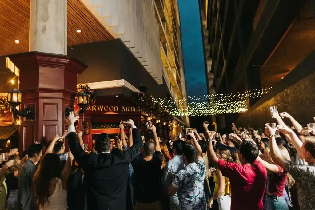 People raising glasses under string lights outside Garwood Arms.