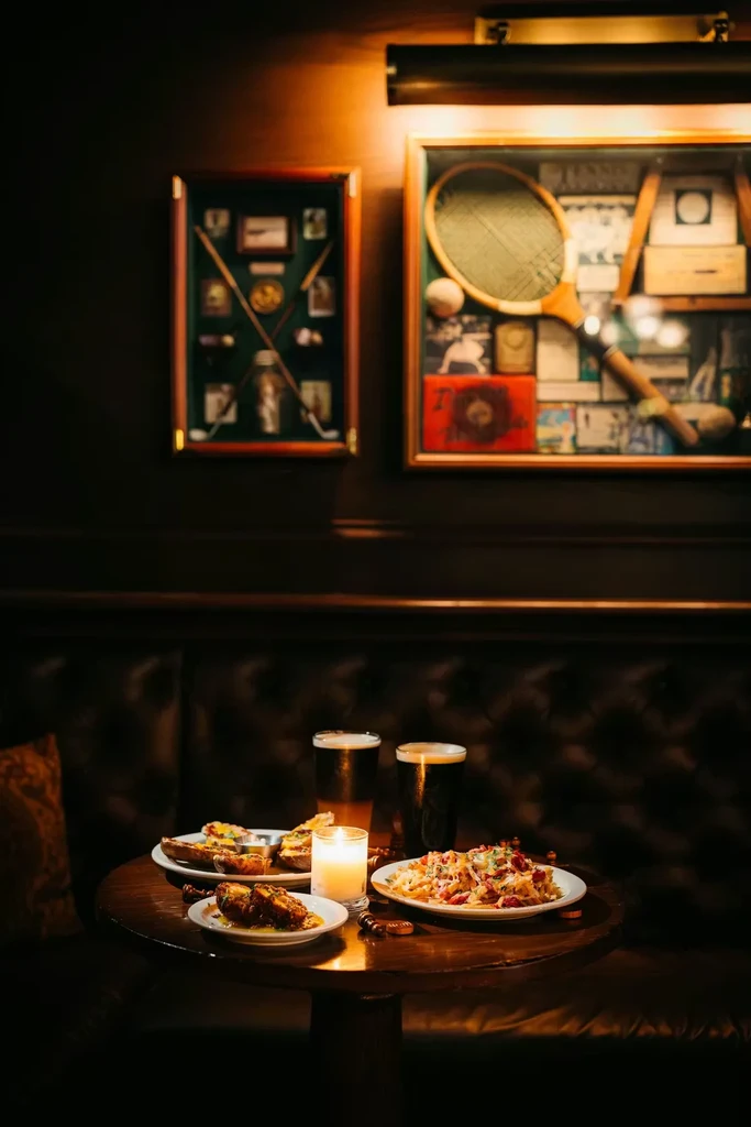Dimly lit table with food, beer, and sports memorabilia.
