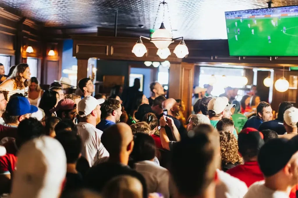 A crowded, traditional pub with people watching soccer on TV.