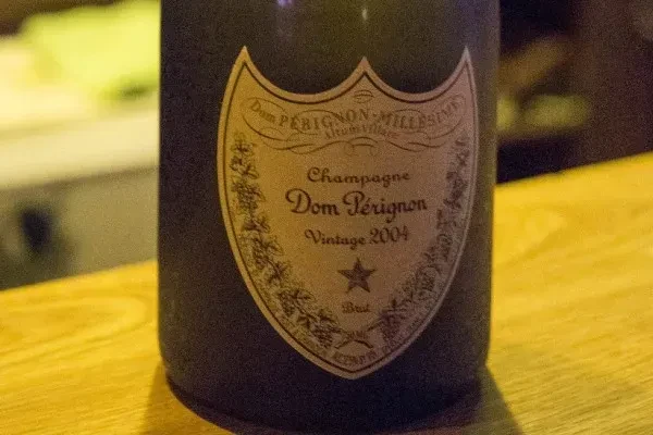 Close-up of Dom Pérignon Vintage 2004 Champagne bottle on a wooden surface.
