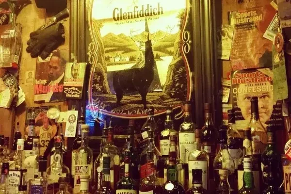 Bar wall displaying whiskey bottles, a stag mirror, and controversial sports memorabilia.