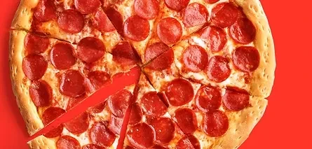 Whole sliced pepperoni pizza with one slice separated on red.
