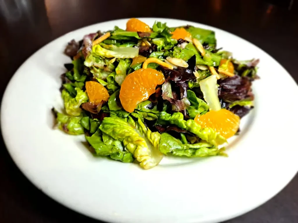 Vibrant lettuce salad with mandarin oranges and nut slivers.