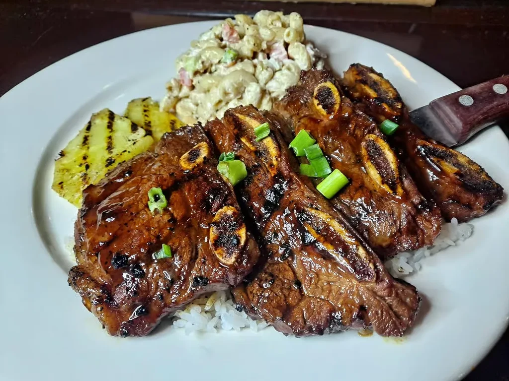 Plate of glazed grilled short ribs, rice, pineapple, and macaroni salad.