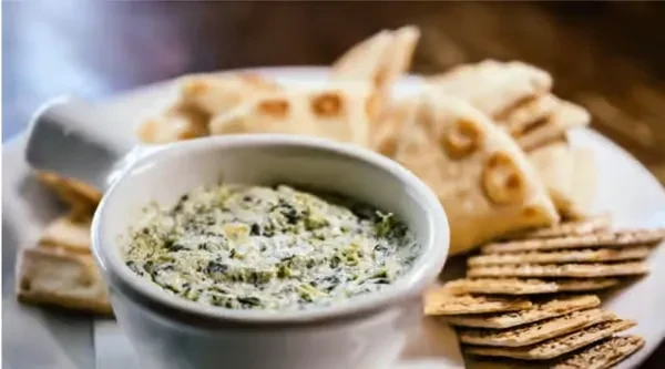 Creamy green dip served with triangular flatbread and seeded crackers.