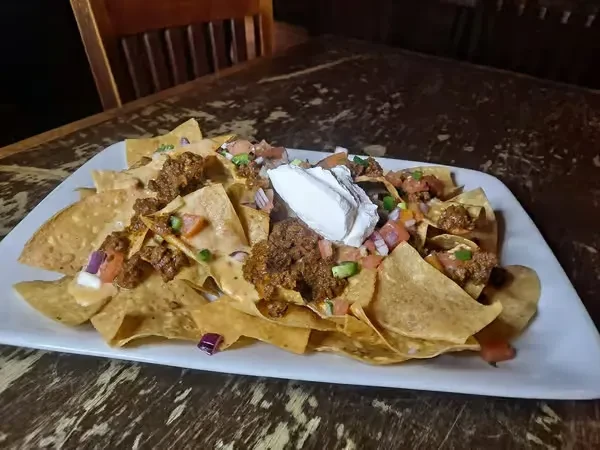 Nachos topped with cheese, ground meat, pico de gallo, and sour cream.