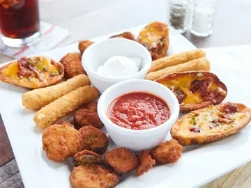 Platter of fried appetizers, potato skins, and two dips on a rustic table.