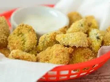 Crispy fried appetizers in a red basket with creamy dipping sauce.